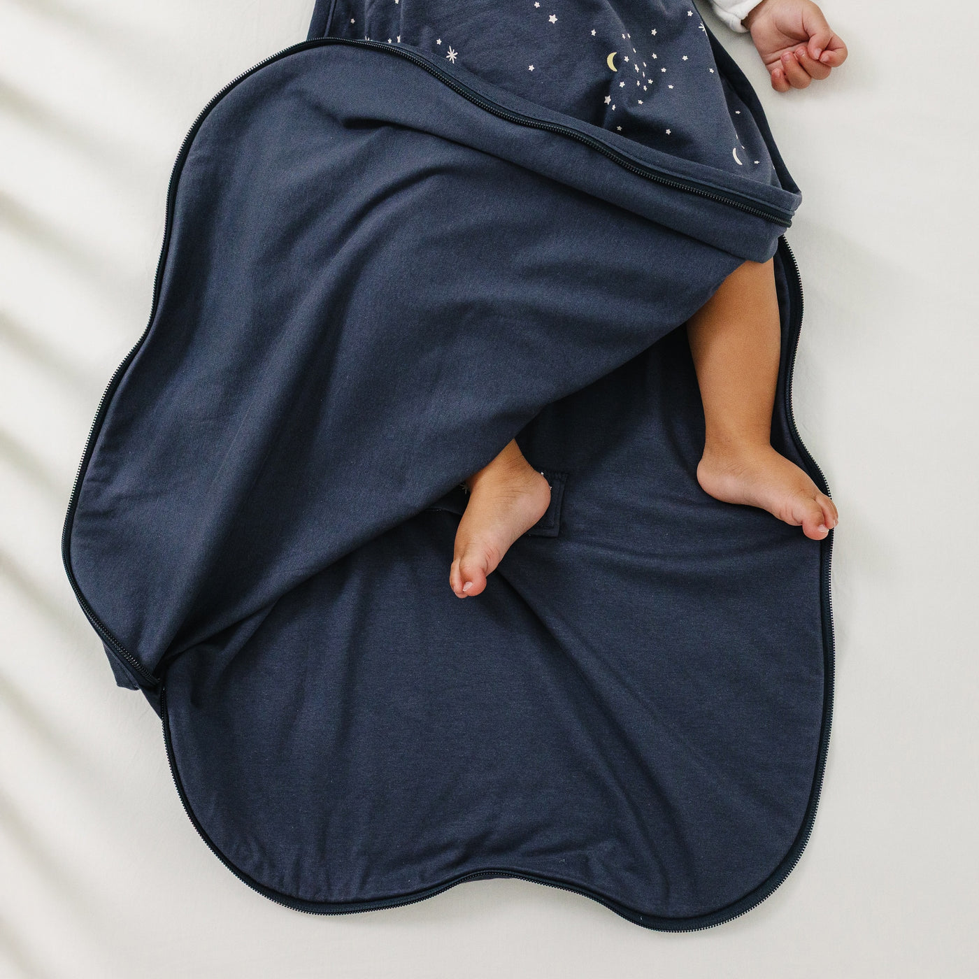 Navy blue Ecolino baby swaddle blanket with a child's feet peeking out on a white background