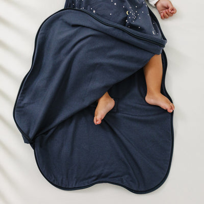 Navy blue Ecolino baby swaddle blanket with a child's feet peeking out on a white background