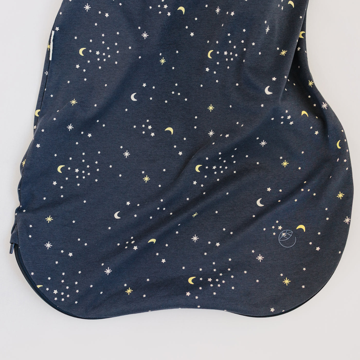 Bottom part of navy blue organic cotton sleep sack with a celestial pattern on a white background