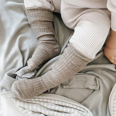 Close-up of baby legs wearing wool socks on a soft blanket